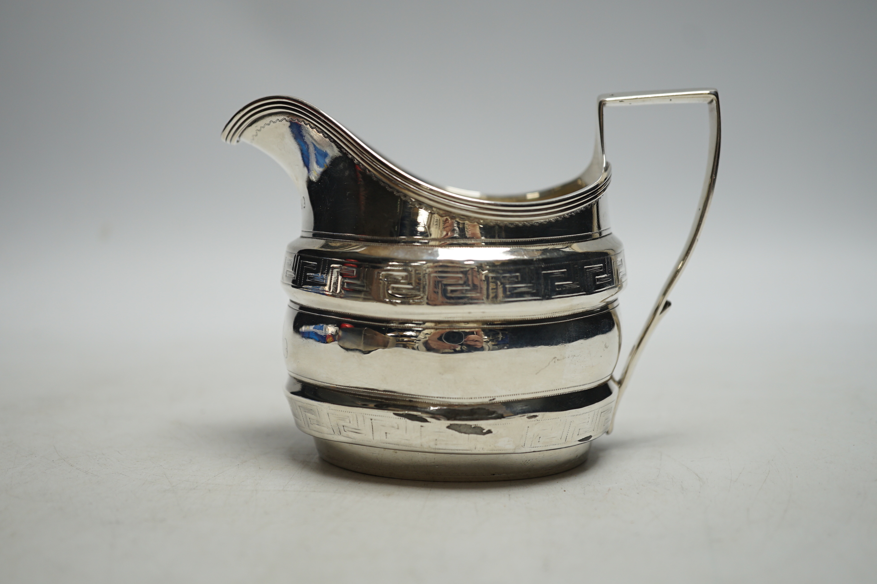 A George III silver helmet shaped cream jug, with engraved key pattern band, London 1804, 9cm. (a.f.)